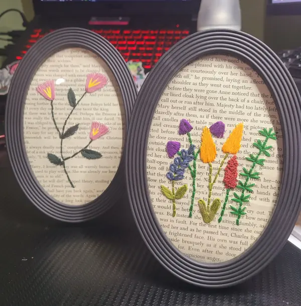 Two framed wildflower embroideries stitched on book pages