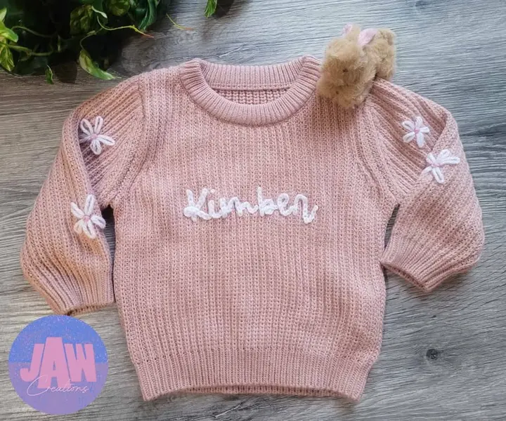 Pink knit sweater with an embroidered name and flowers