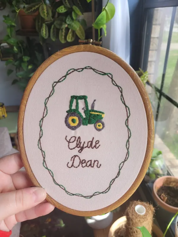 Embroidery hoop with a green tractor and the name Clyde Dean
