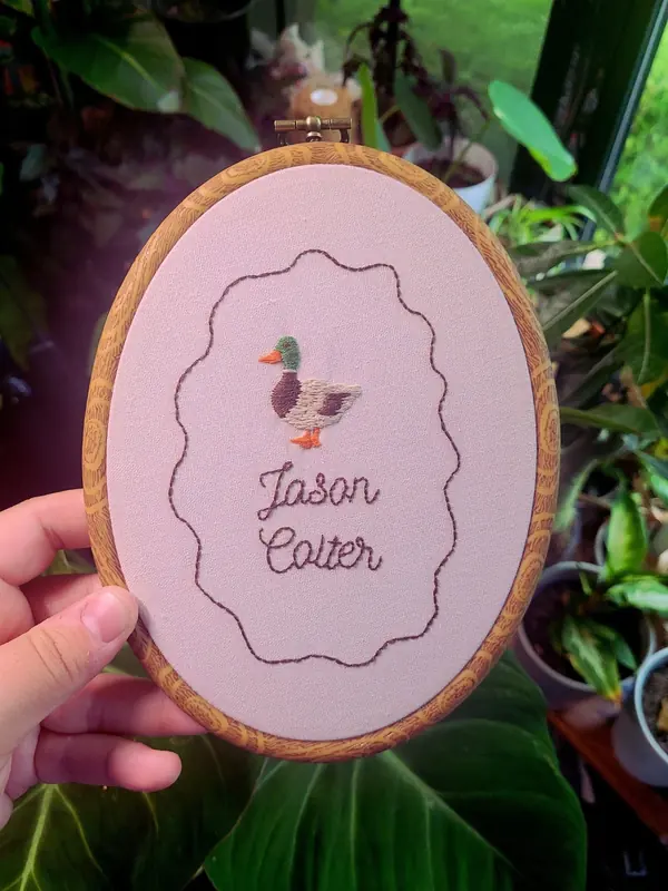 Embroidery hoop with a duck and the name Jason Cotter