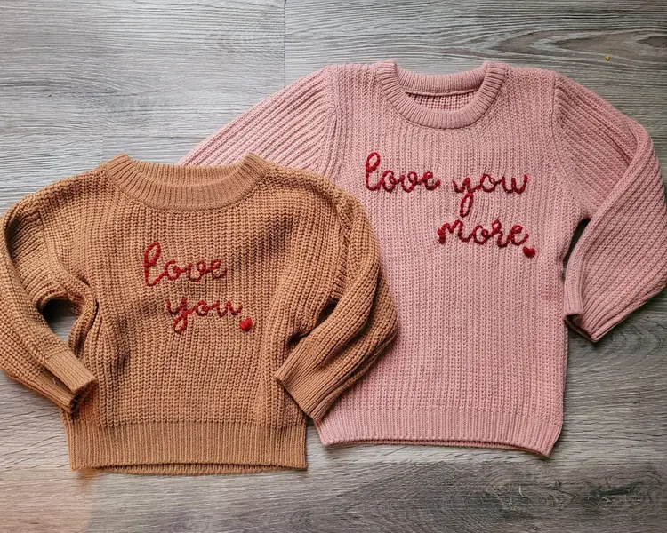 Two kids' sweaters embroidered with love you and love you more
