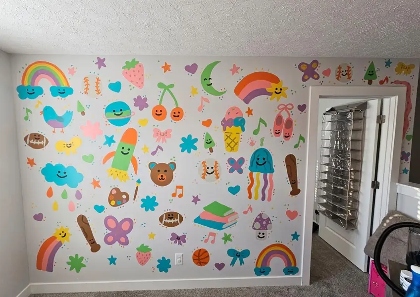Playroom wall painted with rainbows, treats and colorful doodles