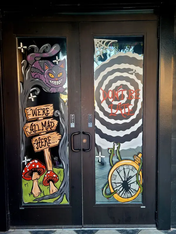 Theatre doors painted with We're All Mad Here and a grinning cat